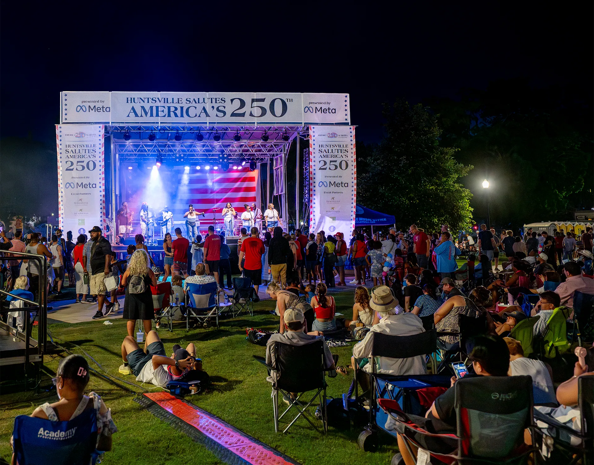 Nighttime crowd watching a live event with concert lighting at Huntsville Celebrates America's 250th.