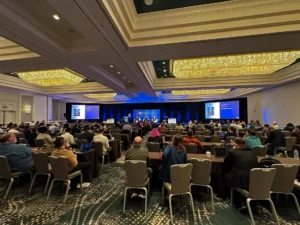Audience seated and listening to a panel discussion in a large conference room.